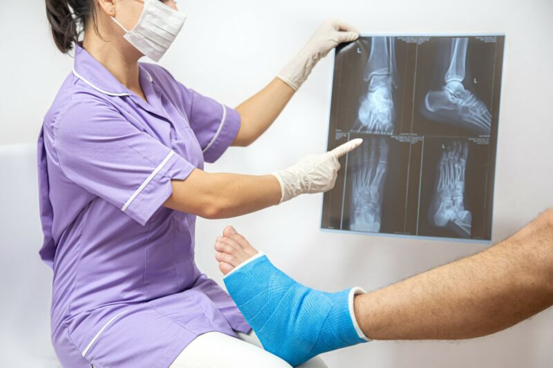 homme le pied fracturé se fait examiné par une femme docteur