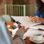 femme souriante qui donne des documents a un homme face a elle