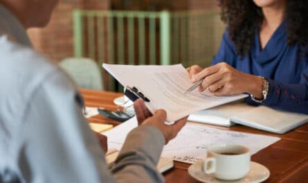 femme souriante qui donne des documents a un homme face a elle