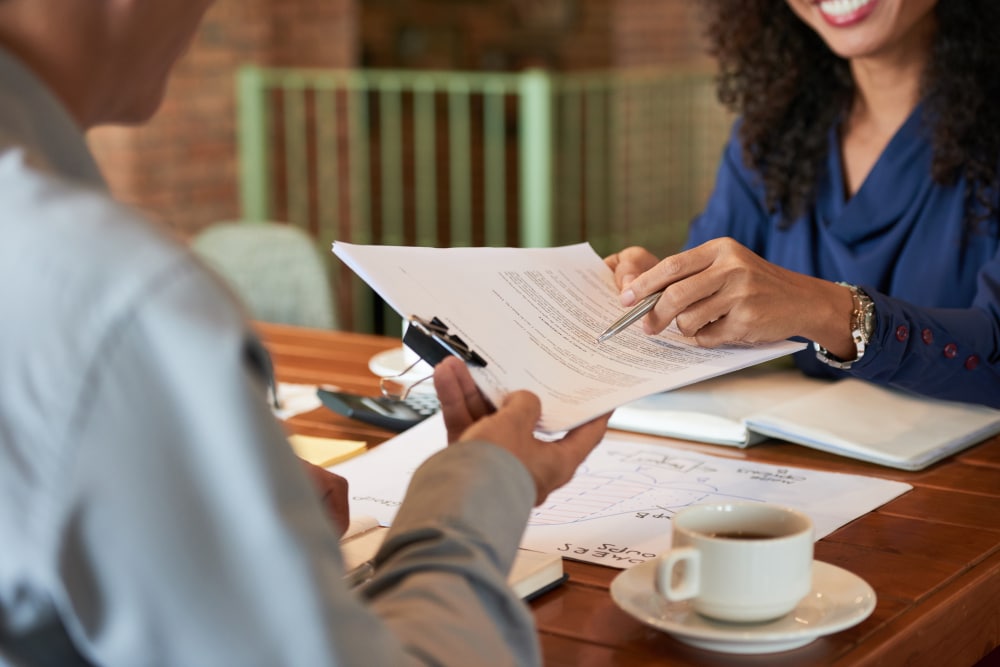 femme souriante qui donne des documents a un homme face a elle