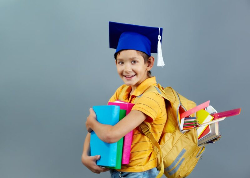 écolier souriant avec son sac sur le dos et des classeurs dans les bras