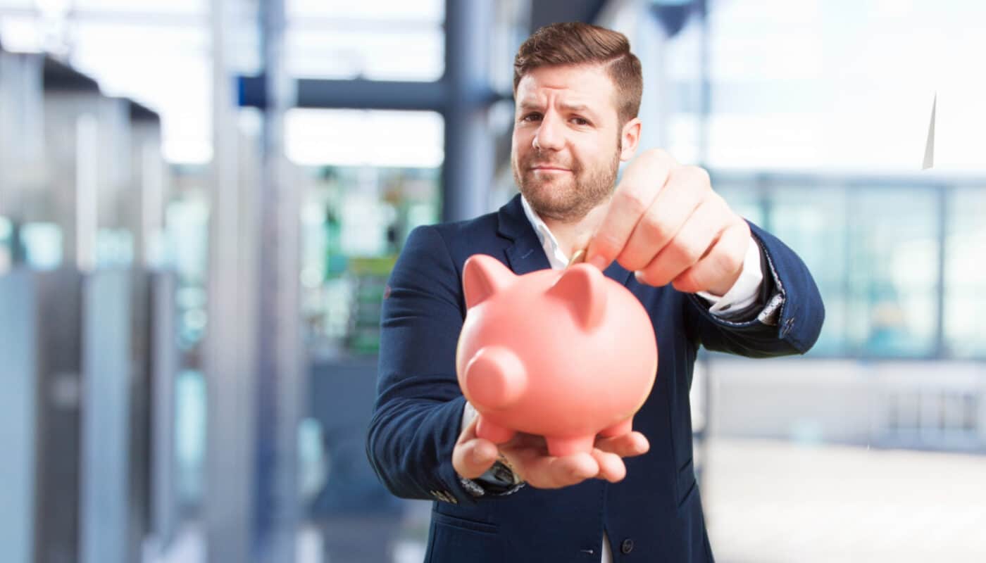 homme qui mets de l'argent dans sa tirelire cochon